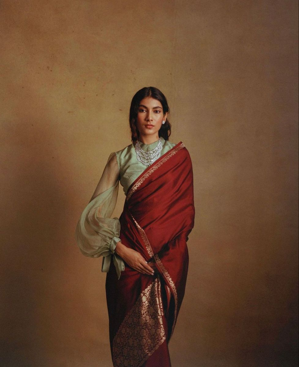 A woman in a flowing red kaftan in a teal-walled interior with a brass Genesis sign